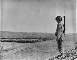 Der amerikanische Gefreite Paul Drop bewacht ein Lager, in dem Kriegsgefangene aus den Kämpfen im Ruhrgebiet untergebracht sind. Fotografie der US-Armee, 21. April 1945. Quelle: National Archives Washington, DC.