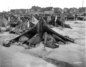 Viele der Rheinwiesenlager grenzten sehr nah an Ortschaften, wie hier in Ludwigshafen-Rheingönheim, wo die Zäune direkt an die Häuser reichten. Fotografie der US-Armee, 28. Mai 1945. Quelle: National Archives Washington, DC.